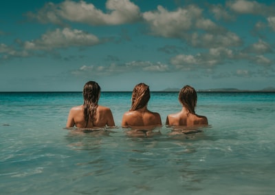 Three women looking at the white clouds in the water under the sea
